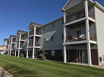 A row of apartment buildings with balconies and a grassy area in front of them
